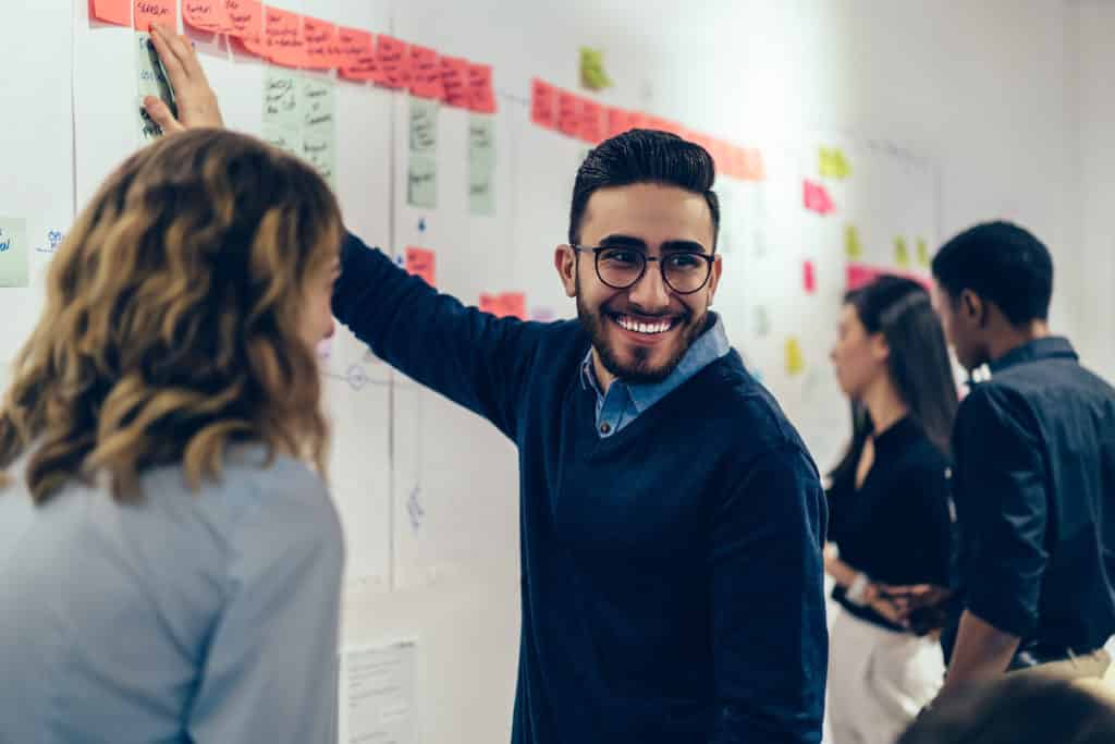 Positive young man smiling while collaborating with colleagues on presentation