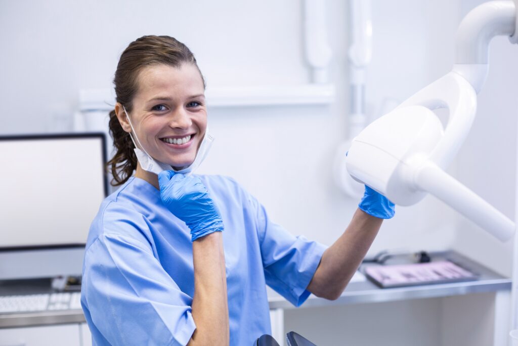 Smiling dental assistant adjusting light Smiling