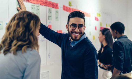 Positive young man smiling while collaborating with colleagues on presentation